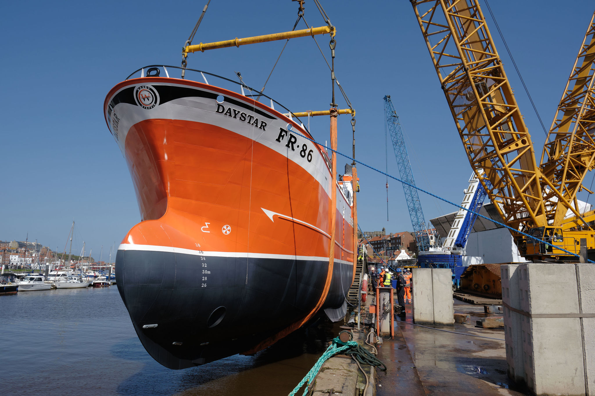 A large vessel is being lifted by cranes into the water in Whitby. Image credit: Parkol