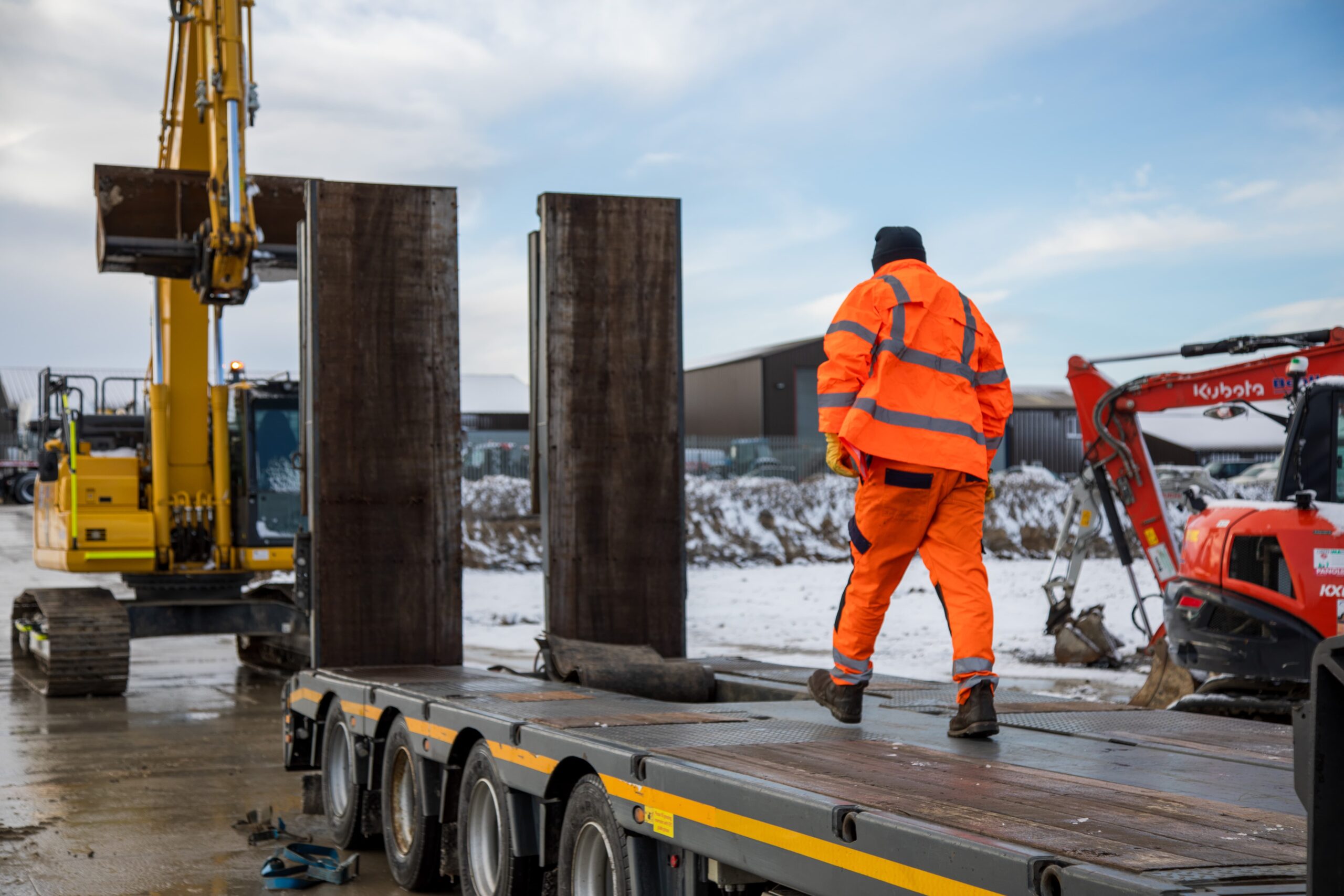 A worker in high‑visibility clothing walking across a trailer.