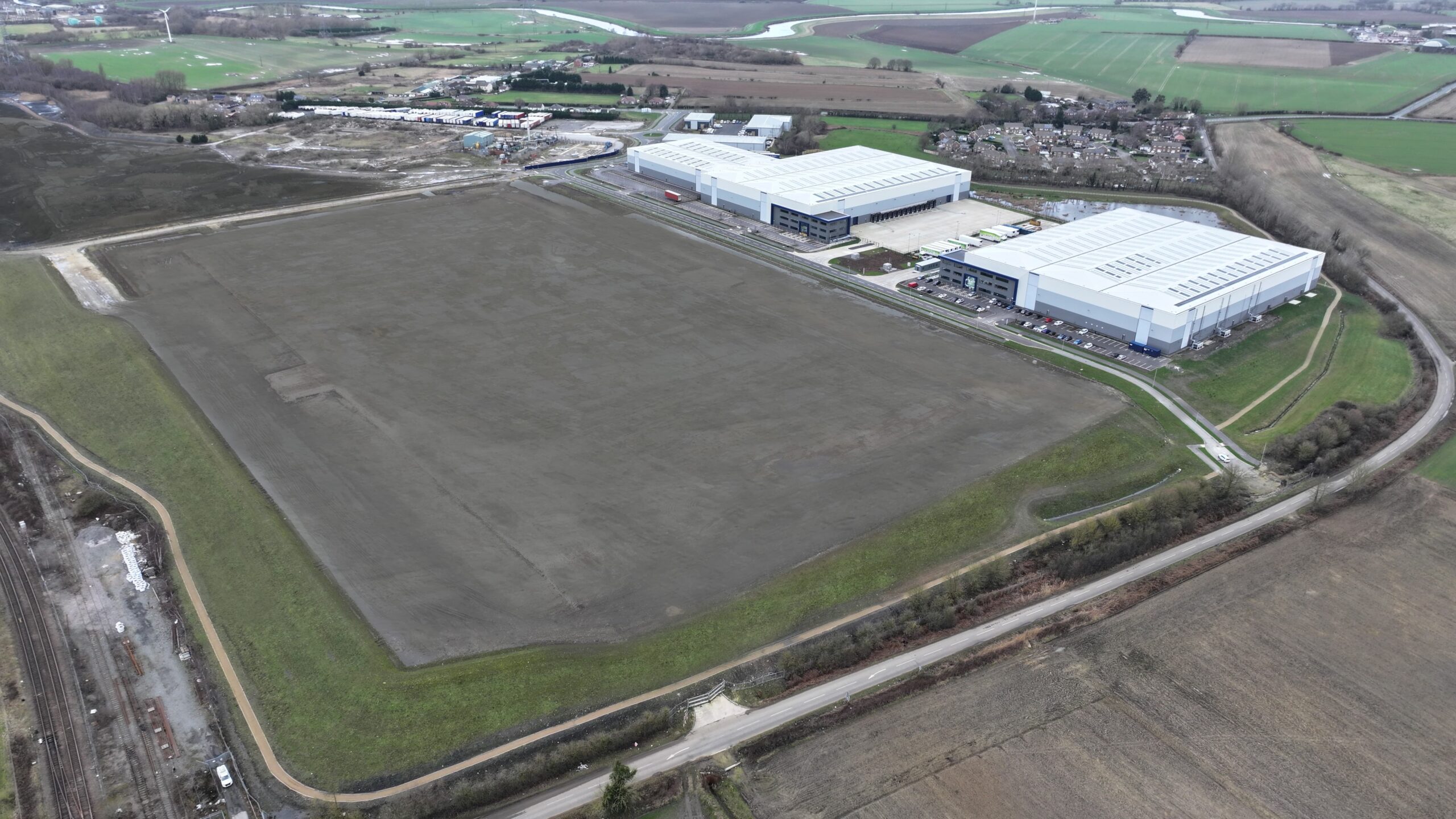 Aerial photograph showing large brownfield space with industrial units located in the distance.