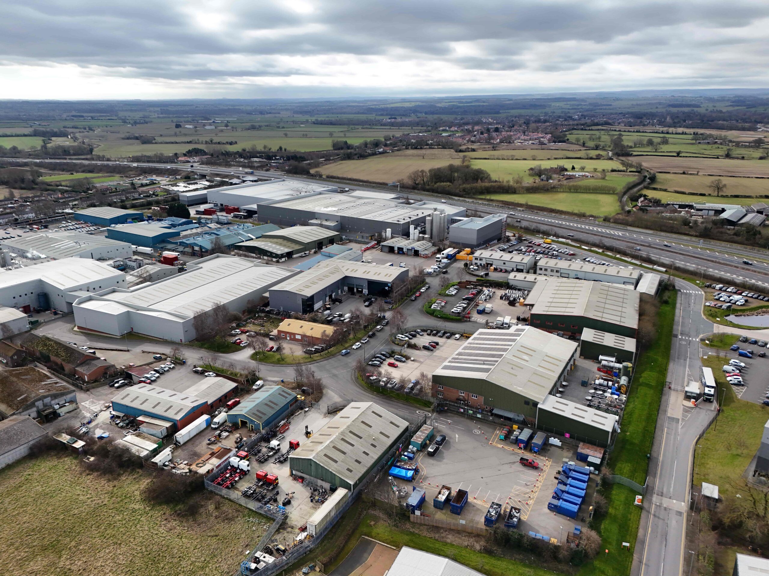 Aerial photograph of the Leeming Bar Industrial Site showing industrial units and traffic movements with green fields in distance