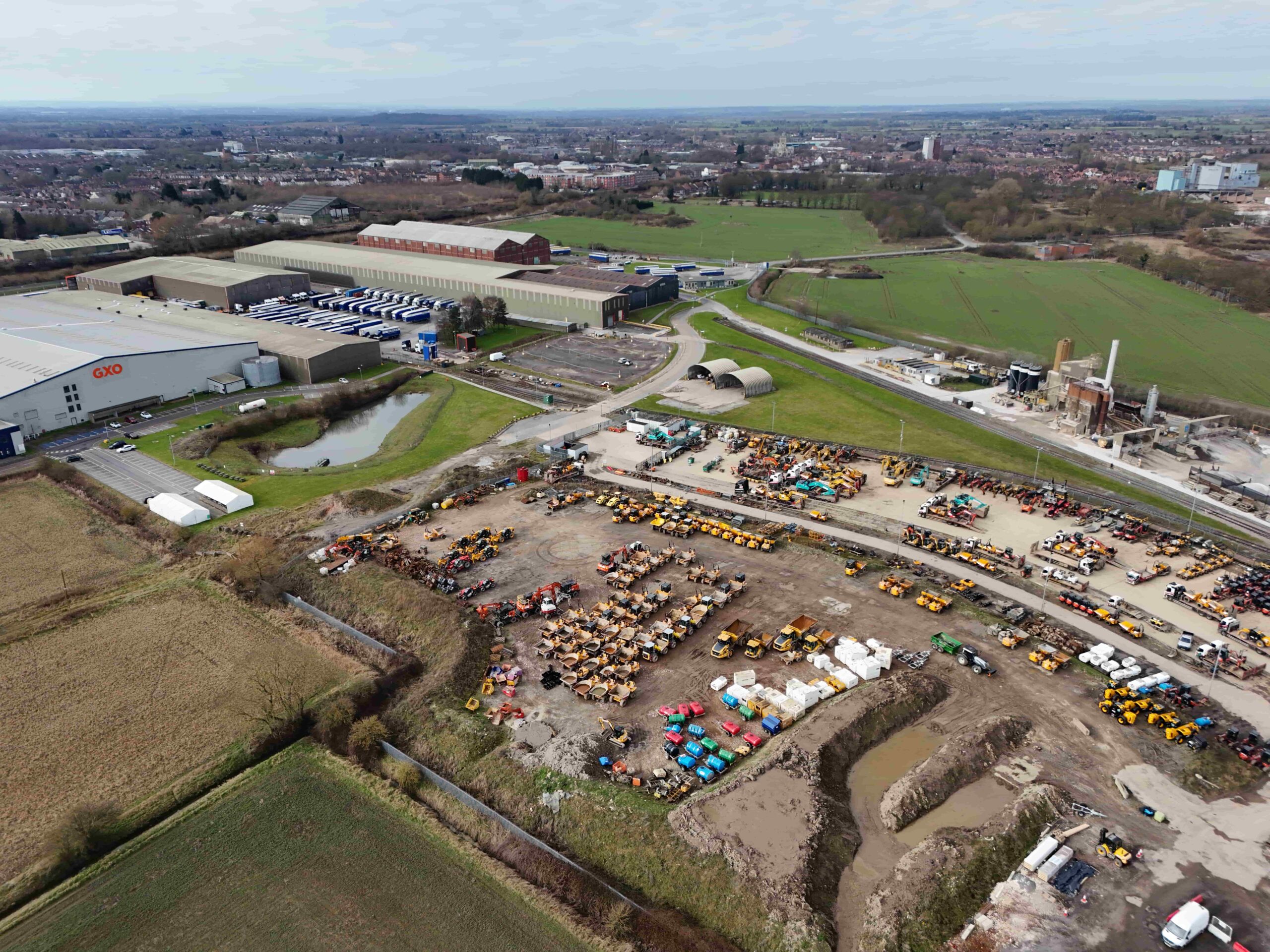 Aerial photograph showing large industrial units in the background and open vehicle storage space in the foreground