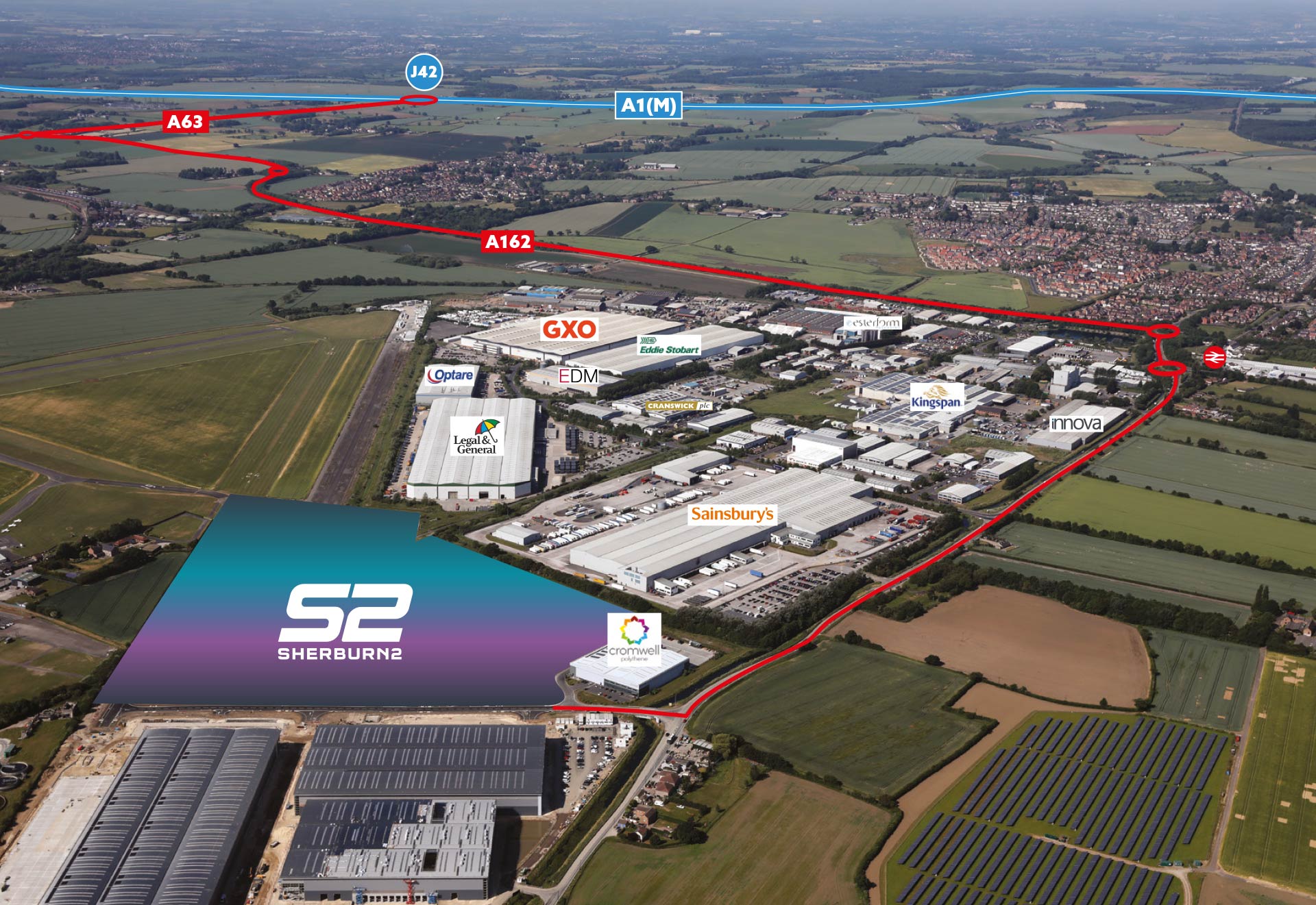 Aerial photograph showing industrial units with green fields surrounding them and key transport routes in the distance.