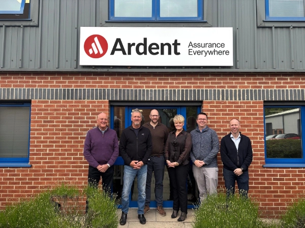 Group of six people standing outside the Ardent building beneath a sign reading “Ardent – Assurance Everywhere”, in front of a brick and metal-clad office premises.